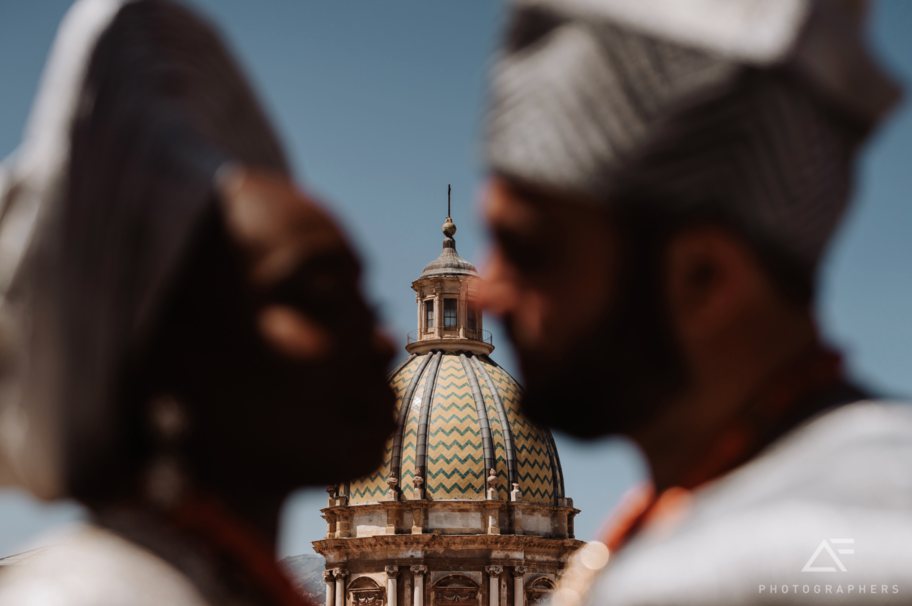 A tiled church dome in Palermo, Sicily, framed between a bride and groom
